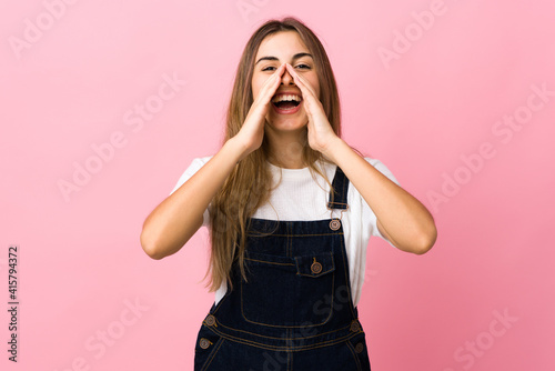 Young woman over isolated pink background shouting and announcing something