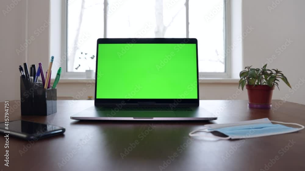 Green screen laptop computer sitting on a home work desk. Moving closeup shot. Green screen laptop computer sitting on a home work desk. Moving closeup shot.