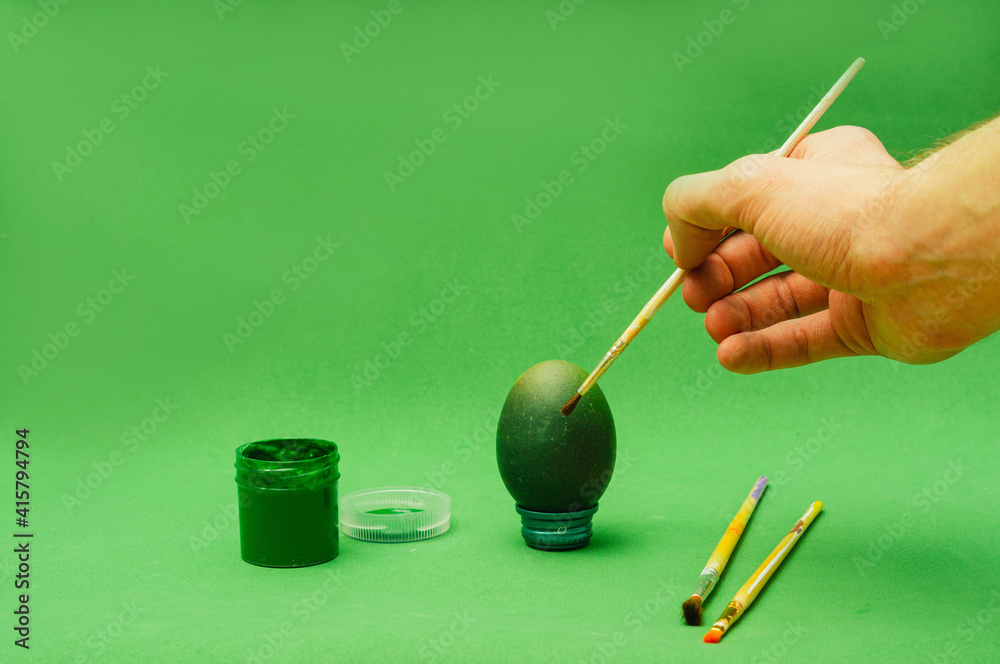 Man hand paints Easter egg with brush Man hand paints Easter egg with brush