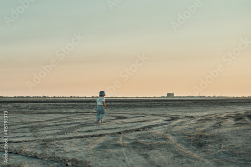 A two-year-old child walks along the dry bottom of the lake. Summer walking in the fresh air.