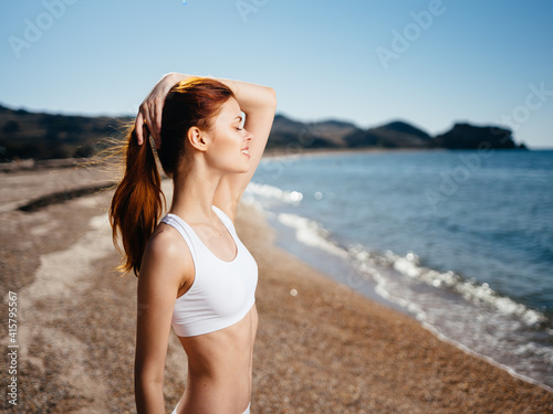 A woman in a white bathing suit walks along the beach island landscape sun