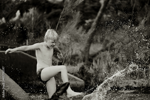 Black and white image of boy swimming in fresh water river with at dusk in New South Wales, Australia