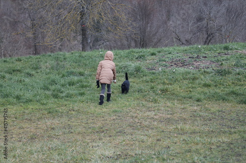 Un enfant en jaquette chaude brune s'approche d'un chat noir © Marc