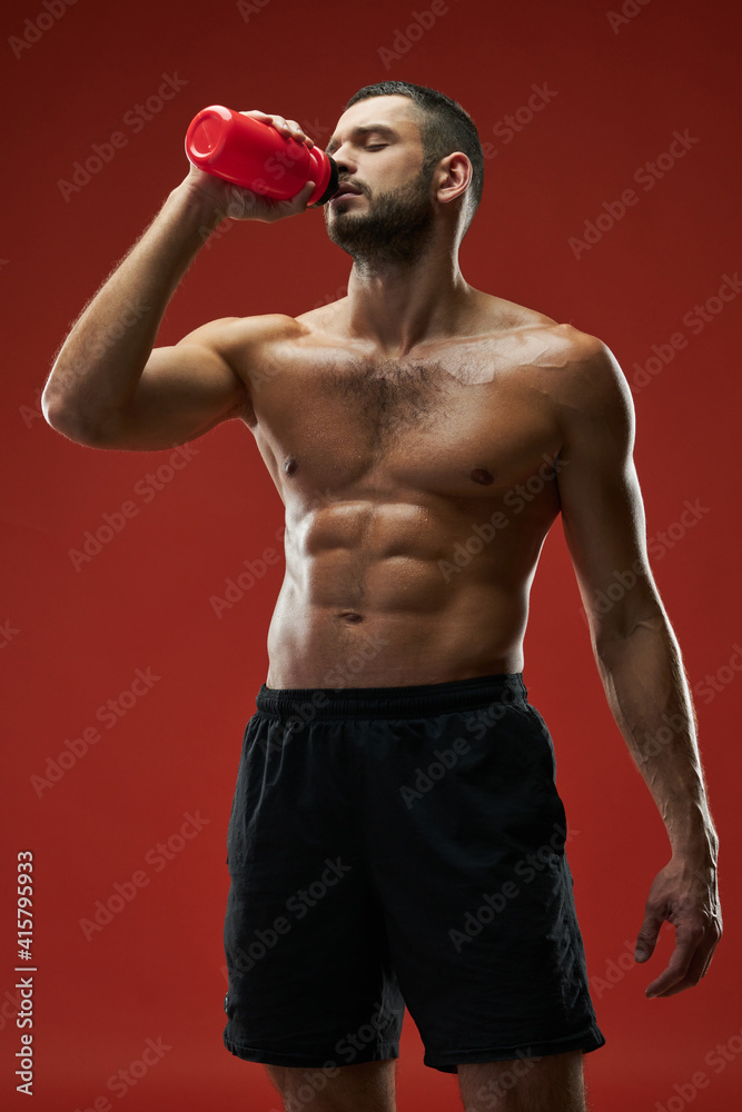 Adult bearded athlete man posing at the camera on red background