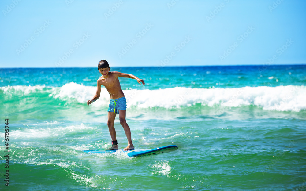 Happy boy ride surfboard on waves confidently surfing photo over sea Happy boy ride surfboard on waves confidently surfing photo over sea