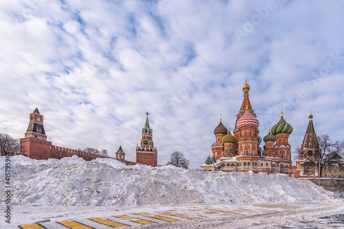 The snowdrifts on Vasilyevsky Spusk after heavy snowfall.  St. Basil's Cathedral, the famous Spasskaya Clock Tower and wall of the ancient Moscow Kremlin against a blue sky. Russia, Moscow photo
