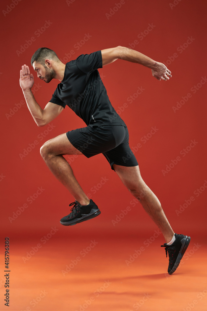 Fototapeta premium Strong sportsman in black shirt and shorts doing exercises in sport club