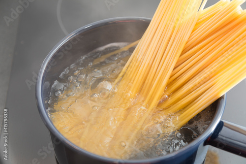 Spaghetti pasta boiling in cooking pan on stove.