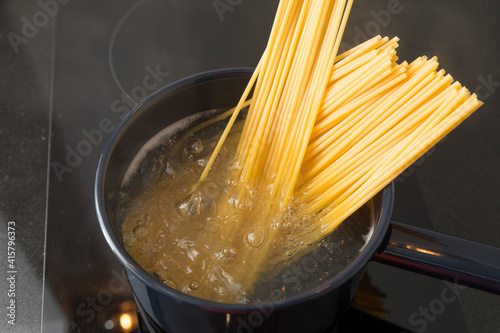 Spaghetti pasta boiling in cooking pan on stove.