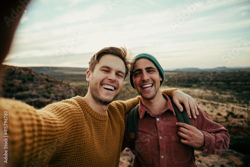 Caucasian male friends hiking in wilderness taking selfie with cellular device embracing the outdoors