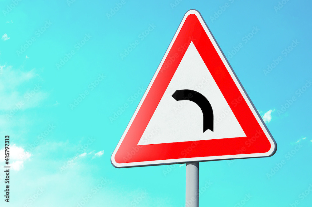 Segnale stradale triangolare di pericolo: curva pericolosa isolato su un palo stradale. Cielo sullo sfondo Segnale stradale triangolare di pericolo: curva pericolosa isolato su un palo stradale. Cielo sullo sfondo