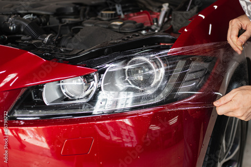 automobile detailing service. protective film on the headlight of the car. © Make_story Studio