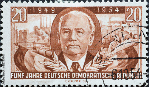 GERMANY, DDR - CIRCA 1954 : a postage stamp from Germany, GDR showing a portrait of Wilhelm Pieck, first President of the GDR; Flags; Böhlen gasoline plant and tractor. Text: 5 years of the GDR photo