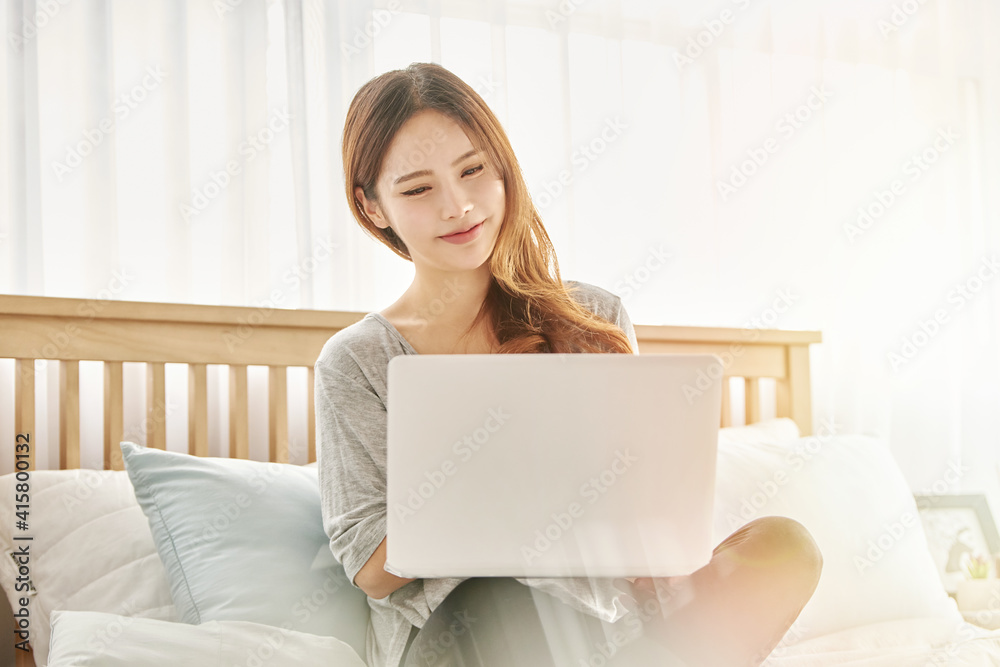 동양인 한국인 아름다운 여성 모델 침대위에서 노트북을 보며 휴식, 쇼핑, 화상채팅 