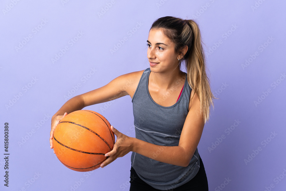 Young hispanic woman over isolated purple background playing basketball Young hispanic woman over isolated purple background playing basketball