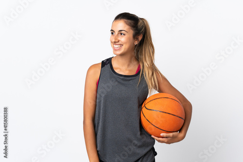 Young hispanic woman playing basketball over isolated white background looking side
