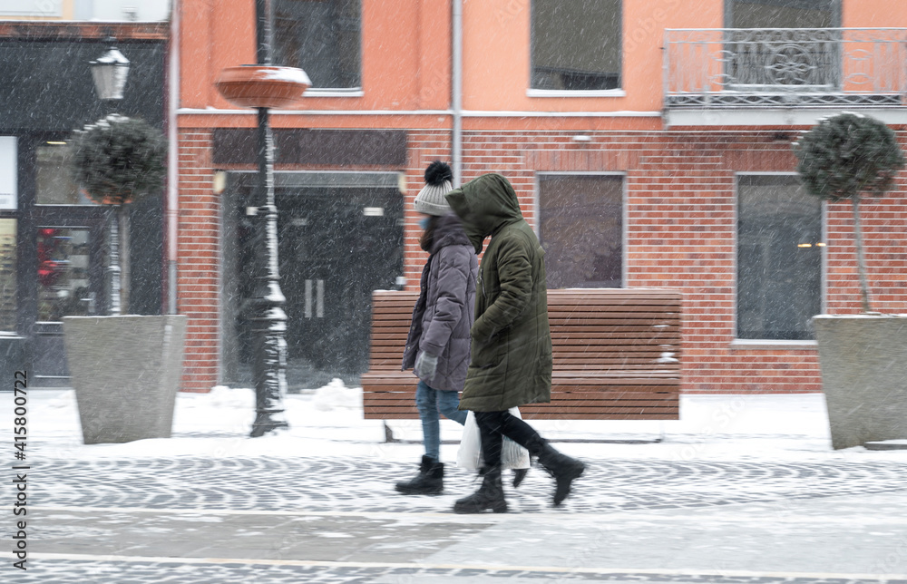 Busy city people going along the street in winter snowy day