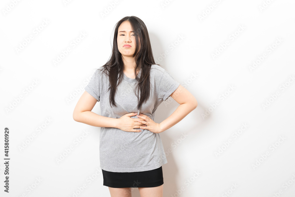 Young asian woman wearing casual clothes with hand on stomach because nausea, painful disease feeling unwell. Young asian woman wearing casual clothes with hand on stomach because nausea, painful disease feeling unwell.