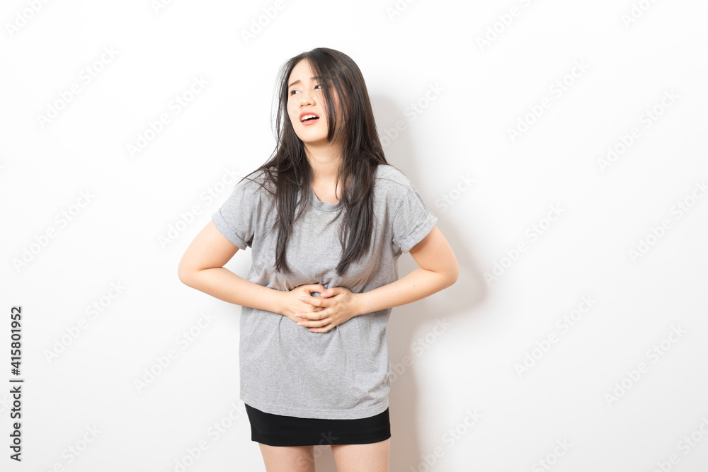 Young asian woman wearing casual clothes with hand on stomach because nausea, painful disease feeling unwell. Young asian woman wearing casual clothes with hand on stomach because nausea, painful disease feeling unwell.