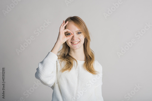Portrait of a stylish and cheerful girl on a white background in the studio who shows funny grimaces