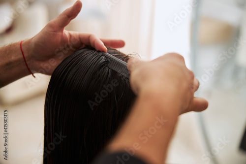 Coiffeur with a hairdressing tool working on the woman hairstyle photo