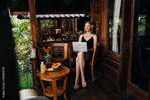 Glad female tourist resting with laptop in cafe