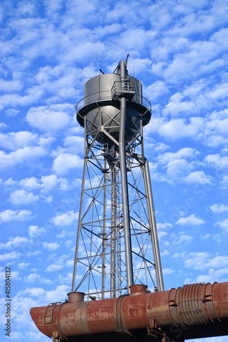 Wassteturm einer stillgelegten Industrieanlage vor blauem Wolkenhimmel bei Sonnenschein im Ruhrpott