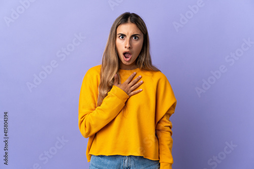 Young hispanic woman over isolated purple background surprised and shocked while looking right © luismolinero