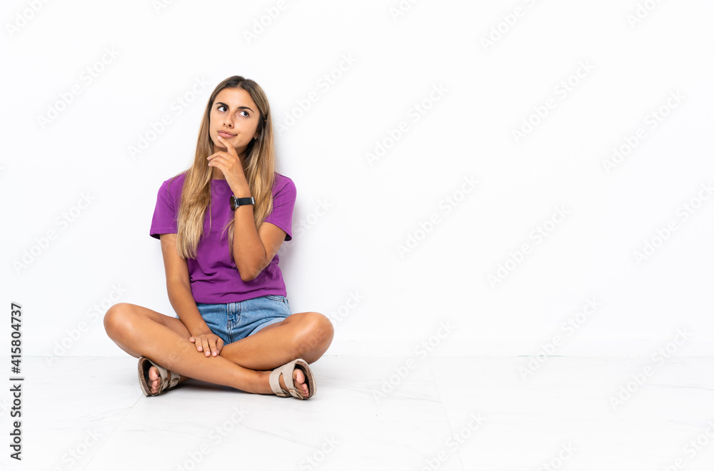 Young hispanic woman sitting on the floor and looking up