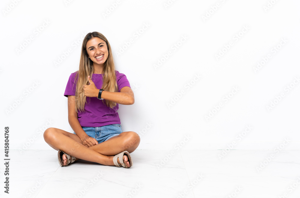 Young hispanic woman sitting on the floor giving a thumbs up gesture Young hispanic woman sitting on the floor giving a thumbs up gesture