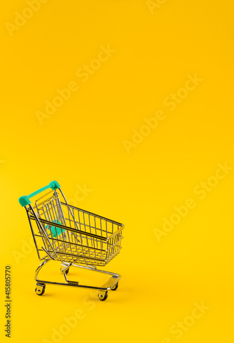Shopping cart trolley on yellow background.