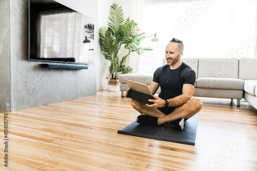 Man on a mat with tablet doing some exercise at home