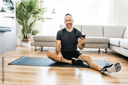 Man on a mat doing some exercise at home using cellphone to help training