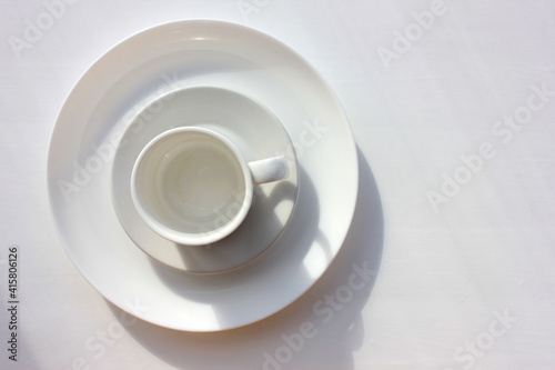 White coffee cup  saucer and plate on white background. Overhead view. Copy space. Set of utensils on table 