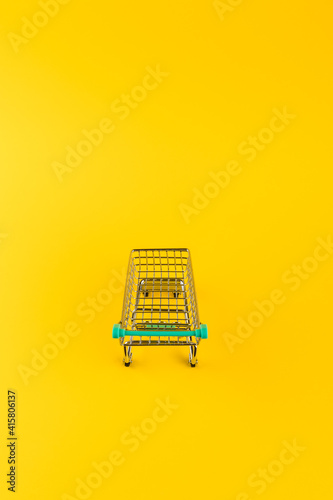 Shopping cart trolley on yellow background.