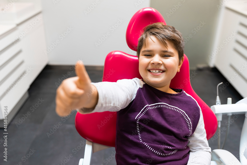 Boy sitting at the dentist chair and showing thumbs up Boy sitting at the dentist chair and showing thumbs up