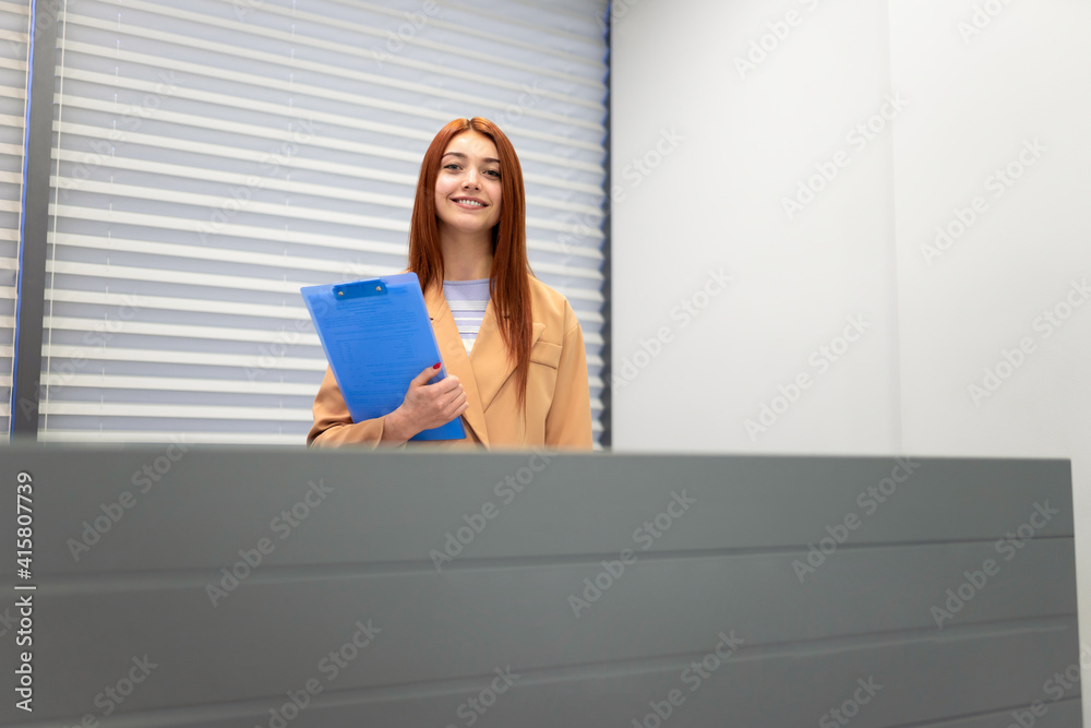 Secretary with clipboard in hands stands at the office reception Secretary with clipboard in hands stands at the office reception