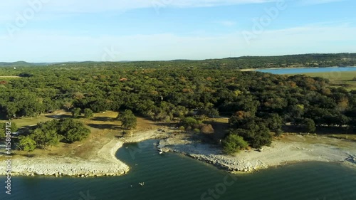 flying over lake medina towards rock shoreline filled with flouring trees photo