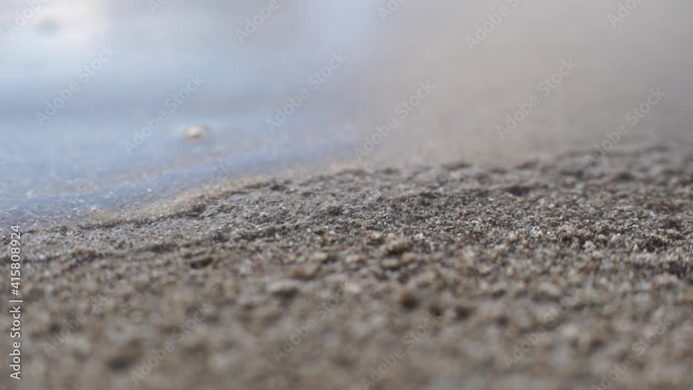 shallow calm sea waves inflow over grey sand macro close up shallow calm sea waves inflow over grey sand macro close up
