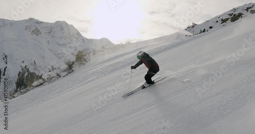 Professional male skier skiing fast ski turns on perfect ski slope in tyrol. Beautiful landscape in the mountains with sporty ski turns in the mountains. Skiing, Snow, Mountains, Alps, Ski shooting.