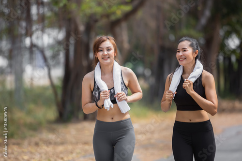 happy two athlete asian girls wear sports uniform are friend together running exercise in green public park, healthy concept.