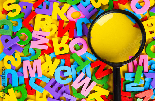 Magnifying glass with colorful alphabet on yellow background, Copy space.Education concept. photo