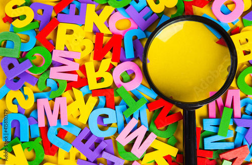 Magnifying glass with colorful alphabet on yellow background, Copy space.Education concept.