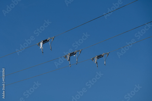 Detail an einer Stromleitung: Drei Kabel / Drähte bei blauem Himmel