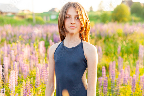 Happy teenage girl smiling outdoor. Beautiful young teen woman resting on summer field with blooming wild flowers green background. Free happy kid teenager girl childhood concept
