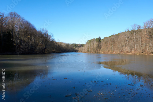 artificial lake with a frozen surface surrounded by trees in the forest