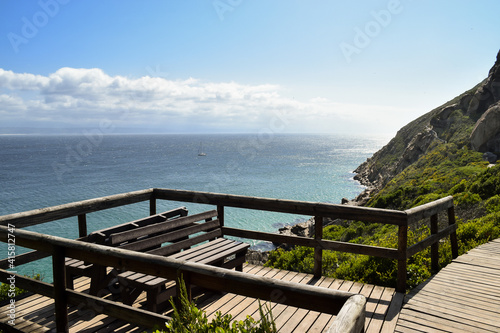 Lookout point with wooden benches overlooking the sea and the mountains in Robberg Nature Reserve, Plettenberg Bay, South Africa.