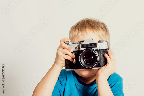 Little boy taking photo with old film camera. Retro technology concept with copy space.