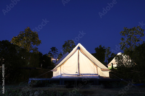 The white tent is camping in the garden at night