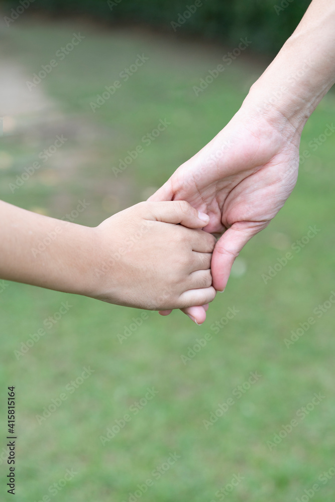 Mother holding a hand of his son in summer day